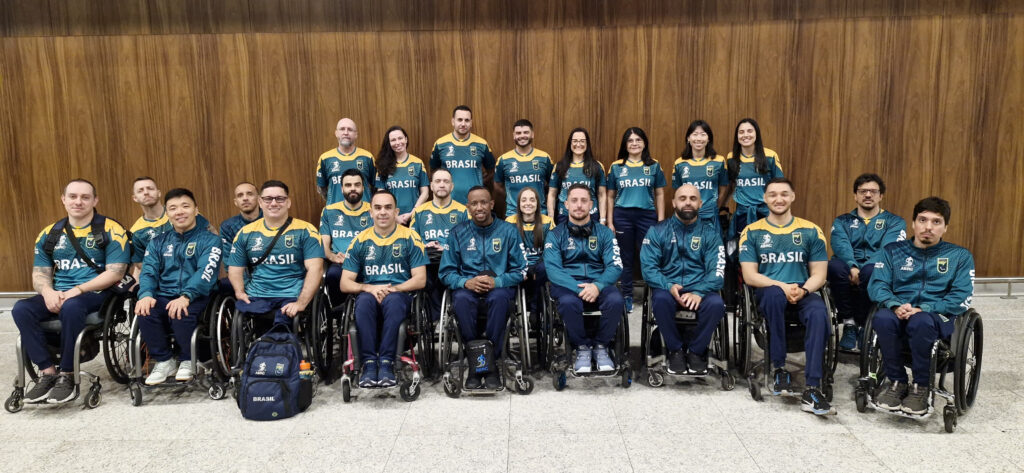 Grupo com cadeirantes e pessoas andantes posando com uniformes verdes escrito Brasil
